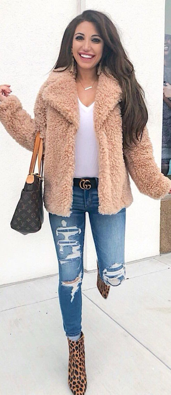 brown winter jacket and distressed blue denim jeans