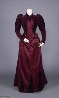2-pc maroon silk velvet & twill silk satin dress c/o bodice w/ shirt collar, asymmetrical pleated front wrap under fans bolero w/ leg o’ mutton sleeves, skirt w/ straight panels pleated & manipulated into W, applied velvet godets at front of skirt, lined w/ silk satin, skirt of silk satin twill, w/ cisele velvet corselet