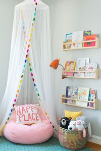 Toddler Reading Nook with spice rack used as book ledges, bean bag chair, and net canopy. Basket for toy storage.