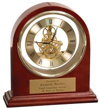 This elegantly luxurious arch grand piano clock award boasts of a rosewood piano finish with brass trimming. It measures 7-3/4 X 9 inches and features a mechanical clock with its skeleton dial visible through the glass. It has a brass plate that can be engraved with the name and award category up to three lines of 30 characters each