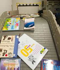 A book falls into an awaiting bin during a demonstration of the automated material handling system given at the Robert Hoag Rawlings Rawlings Public Library by circulation manager Janina Goodwin. The system can handle approximately 750 pieces of media per hour using a radio-antenna system that communicates with the library's database.