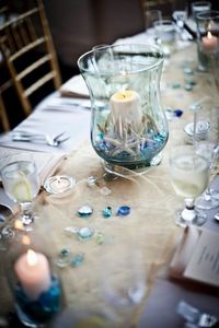 Start your coastal theme tabletop decor with a neutral table runner, then create a display of things coastal on it.... for a stunning table centerpiec.