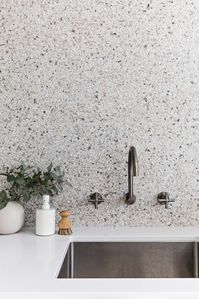 We’re seeing terrazzo used everywhere from kitchen benchtops, to furniture, and of course tiles. Love this terrazzo look version used by Hemma Interiors. Laundry sink styling with speckled splashback, black and white, speckles, gunmetal tapware, laundry tap from wall, laundry tap from splashback, gunmetal tapware on terrazzo tile, modern laundry with a retro twist and indoor plant