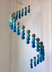 This interesting spiral-shaped nursery mobile, which we call Soothing Sea Tones, is handmade from felt balls with the utmost care. It is beautiful nursery decor and looks fantastic hung above cots or change tables. The nursery mobile is constructed on a wooden hoop and then shaped