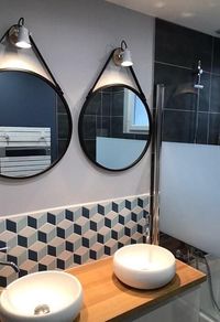 Salle de bain moderne et graphique, miroirs de barbier fixés sur les appliques, crédence géométrique en losanges bleus et gris.