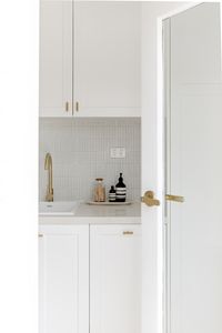 We fell in love with this latest home from talented stylist and Interior Design Liv Frater. Think relaxed Mediterranean for sure! This white laundry with white joinery and shelves, white finger tile splashback and brass tapware is so dreamy! We even love just this small peak of the space through this door! To see more from this coastal house, click on the pin!