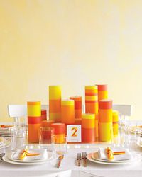 Bold & Modern Fall Table Setting: You'll be blazing a new design path with this clean and contemporary tablescape that takes its cues from the striking beauty of abstract art. A big, vibrant pop of color in the form of bright candles you design yourself casts a warm glow over an otherwise clean, minimalist table. White Pillar Candles, JamaliGarden.com.