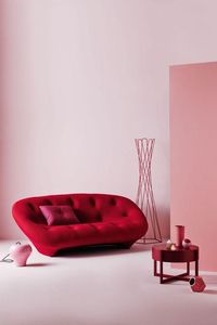 Sculptural red tufted bean sofa, red wire coat rack, red side table, bright bubblegum pink accent wall, and a vignette of modern ceramic vases.