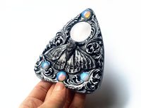 Je suis vraiment fier de vous présenter la pièce maîtresse de ma nouvelle collection, la Planchette de papillon de nuit au clair de lune ! Cette pièce dispose d’un papillon sculpté à la main - et le design en filigrane avec quatre perles de verre opalisées, ce qui rend chaque