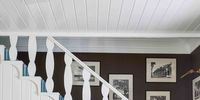 a stairwell painted white with a white table and a gallery wall in the backgroun