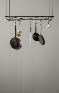 An overhead rack to hang pots, pans and even glasses suspended over the island kitchen helps eliminate the need of a cabinet to store these separately. Image courtesy, Nest