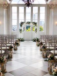 Leaf + Petal NOLA added neutral and blush garden florals and lush greenery to a draped arch for a New Orleans garden wedding at Marche. They also adorned the aisle lanterns with additional blush garden roses.