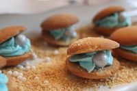 Under the Sea Party Oysters from DIY Louisville made with Vanilla Wafers, Shimmer Sixlets and Pearls, blue frosting, and a sprinkling of graham cracker crumbs.