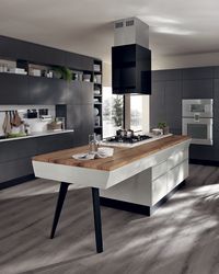 Base units, wall units and open units are in matt Iron Grey lacquer finish. An innovative island brings together the primary #kitchen functions; in fact, a new snack top, veneered in Vintage Oak wood, is integrated into the base of the island with doors, shaped drawers and pull-out baskets (in gloss Light Grey lacquer).