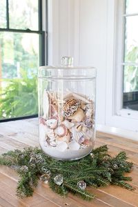 Just add classic Christmas greenery! This is a selection of simple and easy to do coastal Christmas decorations. To see them all, follow the link to Completely Coastal. If you have a fabulous glass jar filled with seashells like this, simple enhance it with evergreens! You could add some fairly lights on top of the shells to for a little sparkle.