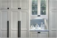 Large transitional u-shaped light wood floor kitchen with a farmhouse sink, white cabinets, white backsplash, stainless steel appliances, an island, recessed-panel cabinets, granite countertops and ceramic backsplash. #mixedcabinets #kitchendesign #traditionalkitchen #traditionaldesign #luxe #glamkitchen #whitecabinets #farmsink #farmhousesink #kitchenchandelier #islandchandelier #islandlighting #blackcountertops #tuxedokitchen