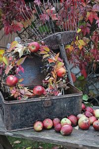 Beautiful fall vignette with a apple wreath, old rake, and a vintage metal box. So pretty with the red leaves and apples.