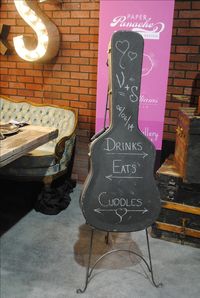 HIPSTER WEDDING Red Events Design Studio Floret Paper Panache Cake Sensations Ed Williams Mens Wear Hipster wedding decor, a guitar case used as a chalkboard for a program