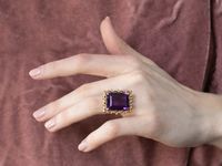 This ring is truly a statement! A large and beautiful deep purple amethyst sits in the center, with an amazing cut and a bold, sparkling color that flickers with bright pops of violet. The stone is expertly cut to really display the stone’s color and sparkle, this looping gold mounting is all this stone needs to frame it to perfection! Metal: 14K Yellow Gold Gem: Amethyst 18.97 Carats Gem Measurements: 18.9 x 15.2 mm, Emerald Cut Ring Size: 5.50
