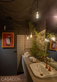 Lavabos It - Adelle Mendes, Raphaela Vilar e Elba Araújo. Ferro, metal e aço oxidado foram os materiais de escolha das arquitetas para criarem um lavabo com o mesmo estilo contemporâneo do It Club. Portas coloridas e pendentes de estilo industrial ficam lado a lado com vegetação e elementos dourados. Todo o conjunto fica imerso em um aroma de terra molhada.