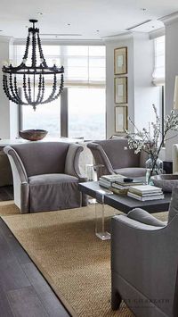 ASHLEY GILBREATH INTERIOR DESIGN: A jaw-dropping modern living room within the penthouse of the Mandarin Oriental of Buckhead, Georgia. A space filled with masculine and feminine touches to create clean lines and inviting moments. When designing the space Ashley used deep, rich grey tones on the upholstery and coffee table while also including gracefully lines in the high back, roll arm chairs and sheer drapery.