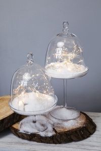 Glitzeraccessoires wie Schneesterne und filigrane Eisblumen, Kugeln aus Glanzkeramik und funkelnde Windlichter verbreiten stillen Winterzauber.