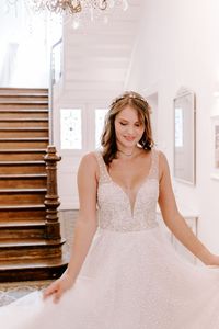 Ein Brautkleid, was es so noch nicht in unserer Kollektion gegeben hat: wie kleine Schneebälle funkeln die aufregenden Pünktchen des Kleides ‘Elsa’ auf sanftem Tüll. Tiefe Ausschnitte und eine herrliche Schleppe runden das Design ab und machen es zu einem aufregenden Blickfang. Eine klassische A-Linie, die sich perfekt für deinen Hochzeitstag eignet und dich wie eine Prinzessin strahlen lässt. Dieses Design eignet sich übrigens auch besonders gut für deine Winterhochzeit.