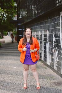 Look plus size usando vestido curto roxo e blazer laranja de alfaiataria sandália laranja e bolsa laranja Cinderela de Mentira