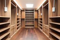 An impressive walk in wardrobe Interior of a modern contemporary house. The timber joinery shelves and cupboards and a timber floor exude quality