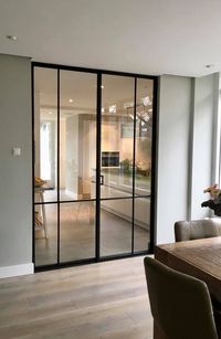 Une séparation élégante entre le salon et la cuisine avec ces 2 portes en verre et leur cadre en aluminium noir.