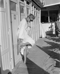 Grace Kelly in bathrobe and sunglasses in front of a beach cabin during the Cannes Film Festival. 1955.