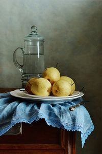 Classic still life with few yellow Asian Pears on blue folded napkin and tall pitcher with water in old kitchen More