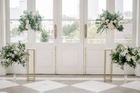 Lush ceremony arrangements of lilies, hydrangeas, garden roses, majolica, and tropical greens in glass fluted vases by Leaf + Petal NOLA for a New Orleans Garden wedding at Marche.