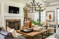 ASHLEY GILBREATH INTERIOR DESIGN: A lake house living room can also be timeless and effortless. The natural textures within this space allow for comfort yet custom draped walls with suspended art framing french doors bring a bit of warmth and softness to the space.