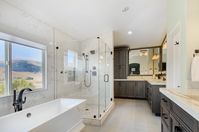 This expansive master bathroom with a view boasts double vanity stations, freestanding tub, shower, separate toilet area and large walk-in closet. #freestandingtub #doublevanity #masterbathroom #bathroomideas #shower #showerideas #stainedcabinetry #spalikeretreat #spa #retreat #soakertub #tub