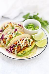 Fresh, delicious Fish Tacos with Honey Lime Cilantro Slaw! My favorite fish taco recipe. This is the BEST! Mildly spicy fish, served with a fresh slaw and drizzled in tomatillo ranch. Don't forget the avocados! #onelovelylife @onelovelylife // Fish Taco Recipe // Tacos // Taco REicpe // Gluten Free Dinner ideas // Healthy dinner ideas //