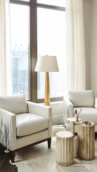 ASHLEY GILBREATH INTERIOR DESIGN: A cozy sitting area with Buckhead skyline in view of this penthouse condo. The modern flare of the fringe leather armchairs paired with traditional elements of the brass cocktail table and Elegant Earth fluted columns atop a white cowhide rug make for a inviting space within this neutral living room.