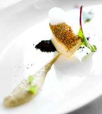 Merluza negra fish cooked sous vide with artichoke hearts cream, sea air and black olive powder.