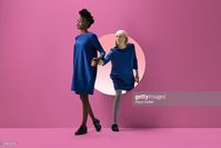Stock Photo : Two women peeking out of round opening in coloured wall