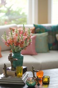 Style your coffee table with a mix of books, an earthy coloured vase with flowers, and colourful votives. Create a point of visual interest by placing antique, brass puja elements. Image courtesy, Sruthi Singh