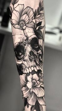 Tatuagem masculina de caveira com flores.