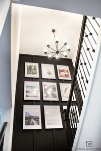 This custom gallery wall took a builder grade staircase into a custom modern look with a bold accent wall and oversized gallery wall. | Black wall | tall ceilings | staircase design | gallery wall ideas |