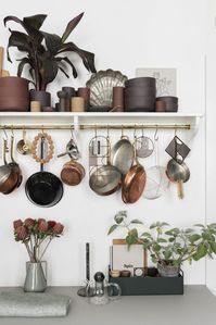 Make the most of your walls sans the cabinets. Place a rod under your floating shelf and hang some hooks from it to suspend pots, pans, ladles, strainers and other utensils you need for daily use. Image courtesy, Nest