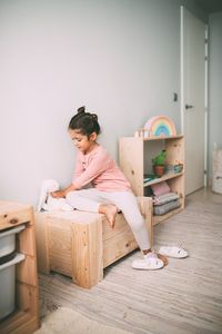 Alejandra jugando sobre un baúl de madera de Muebles Lufe