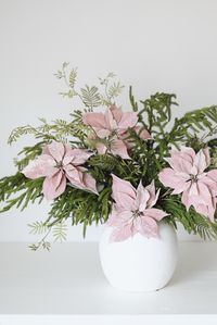 Dreaming of a pink Christmas? Style your favorite real touch Norfolk pine branch with a few pink poinsettias for a stunning, Christmas floral centerpiece. Shop holiday stems and artificial pine stems at Afloral.com.