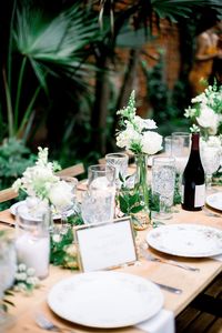 A gorgeous wedding set up at the Pharmacy Museum Courtyard in New Orleans. Leaf + Petal created mixed size bud vases with neutral florals and greens with candles by House of Modern Vintage NOLA