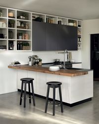 This composition with peninsula, “Melting” breakfast/snack top (Vintage Oak veneer) and a “Fluida” wall system characterized by open and closed front units: Selfmotion wall units and undermounted sink with mixer tap.