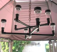 Contemporary style solar outdoor chandelier. Materials - PVC pipe and fittings, white solar lights, wooden knob. Chain and carabiner clip not