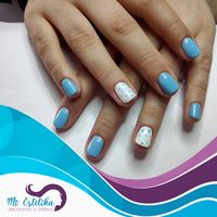 Manicura de uñas con esmaltado permanente de color azul celeste con detalles de lunares