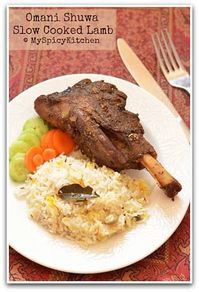 Omani Shuwa - slow cooked lamb on a plate with some salad and flavored rice.